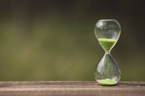 istock hourglass and green blur background 866397578