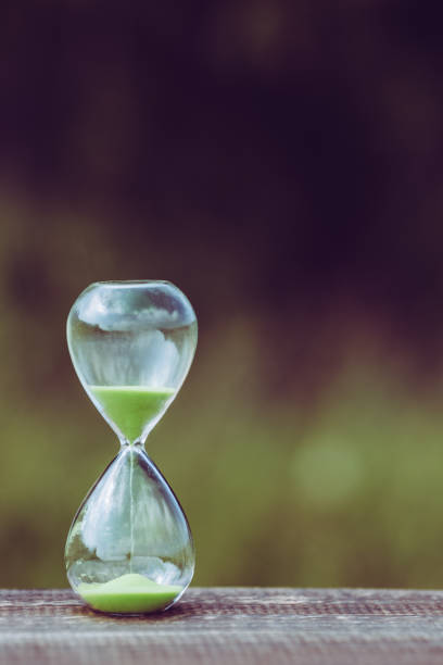istock hourglass and green blur background 866397590