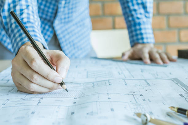 istock Concept architects,engineer holding pen pointing equipment architects On the desk with a blueprint in the office, Vintage, Sunset light.Selective Focus 866408158