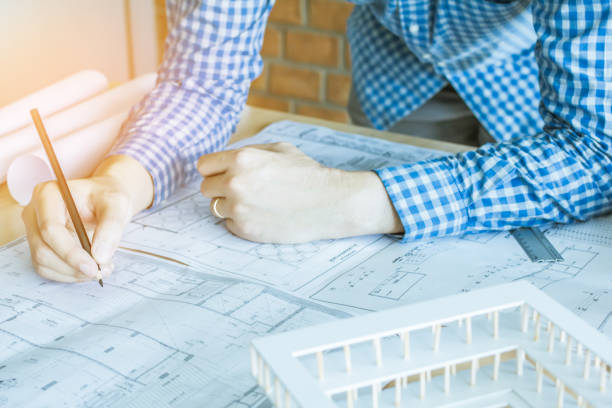 istock Concept architects,engineer holding pen pointing equipment architects On the desk with a blueprint in the office, Vintage, Sunset light.Selective Focus 866408194