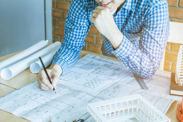 istock Concept architects,engineer holding pen pointing equipment architects On the desk with a blueprint in the office, Vintage, Sunset light.Selective Focus 866408406