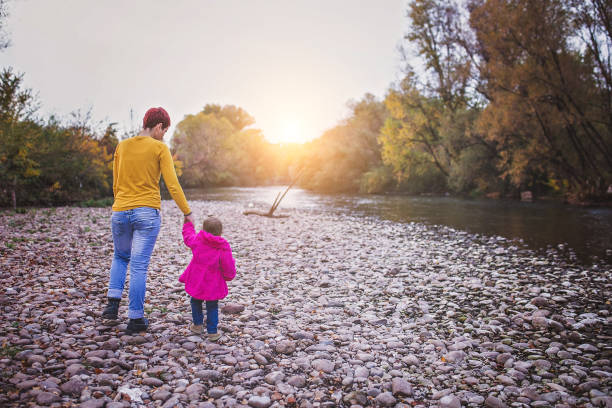 istock Mother and daughter walking by the river 866433532