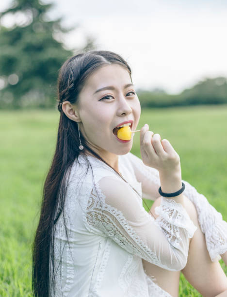 istock woman sitting on meadow eating ice lolly 866436572