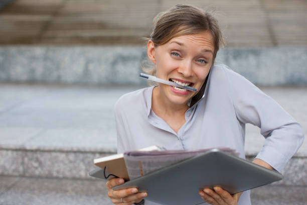 istock Loaded secretary with pen in teeth answering call 866436878