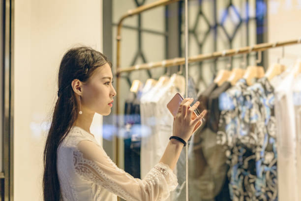 woman standing outside the clothes shop with holding mobile phone
