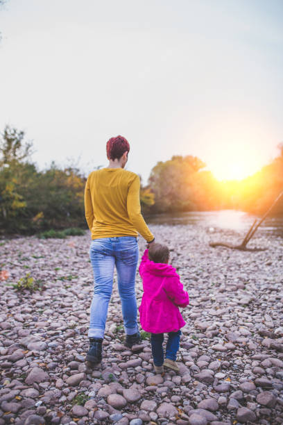 istock Mother and daughter walking at riverside 866444996