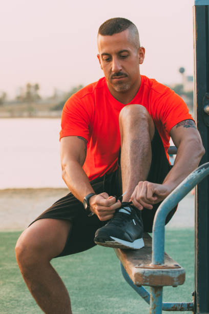 istock Serious young man tying up sneakers on playground 866445150
