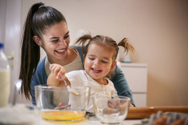 istock Mother and smiling girl baking cookie together. 866459578