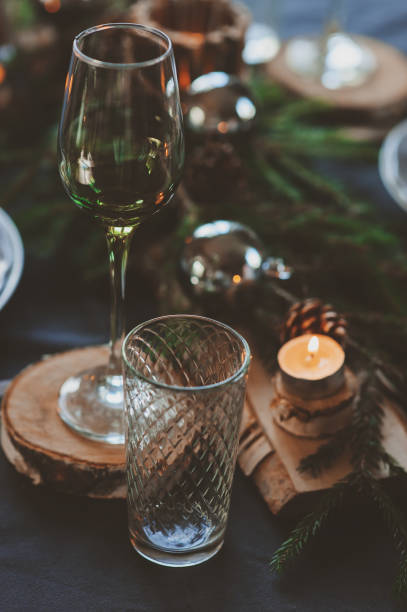 istock Festive Christmas and New Year table setting in scandinavian style with rustic handmade details in natural and white tones. Dining place decorated with pine cones, branches and candles 866462584
