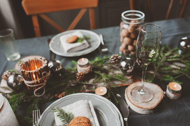 istock Festive Christmas and New Year table setting in scandinavian style with rustic handmade details in natural and white tones. Dining place decorated with pine cones, branches and candles 866462588