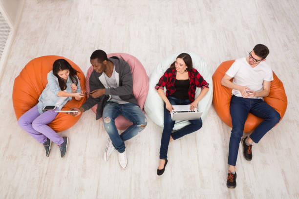 istock Friends using gadgets, sitting indoors in line 866464816