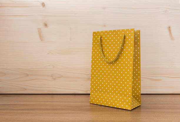 Yellow polka dot paper bag on wood background.