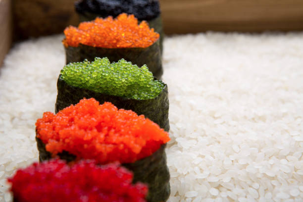 Closeup of sushi gunkan with colored caviar on white rice background and texture copy space