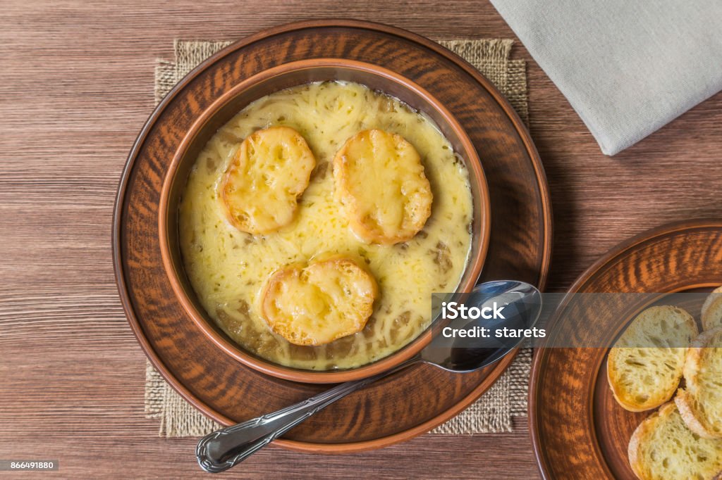 Onion soup with toasted baguette on the table made of oak planks. French food concept. Brown. The view from the top. Copyspace. Onion soup. A dish of French national cuisine. Gratin Stock Photo