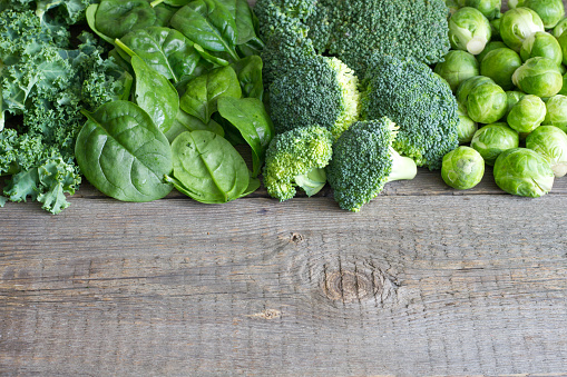 Green vegetables and herbs background concept on wooden board