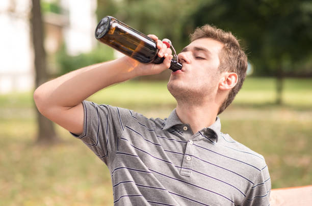 istock Young man drinking a beer in the park 866498072