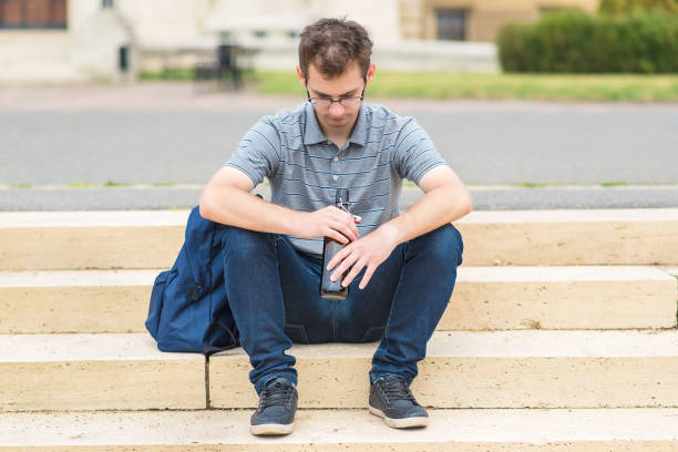 Handsome young man sitting in park with a bottle of beer
