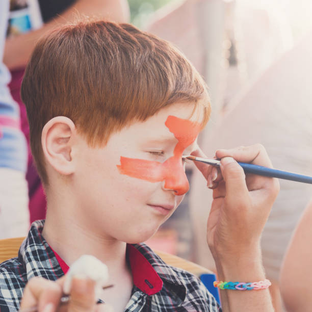 child boy face painting, making tiger eyes process - face paint human face mask carnival imagens e fotografias de stock