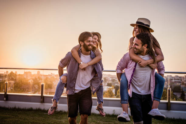 istock Young playful couples piggybacking on a balcony at sunset. 866503416