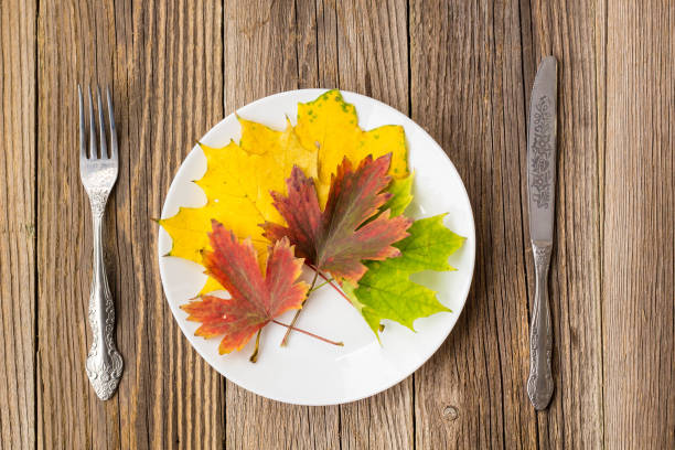 istock Autumn Table setting. Thanksgiving dinner plate with fork, knife and leaves on rustic wooden table background 866503632