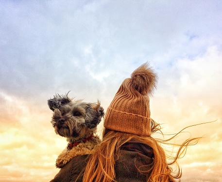 Girl in Wooly Hat holding her dog on a windy day