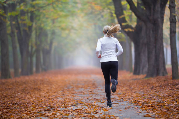 women in sport - rear view woman jogging alone in autumn - prater park imagens e fotografias de stock