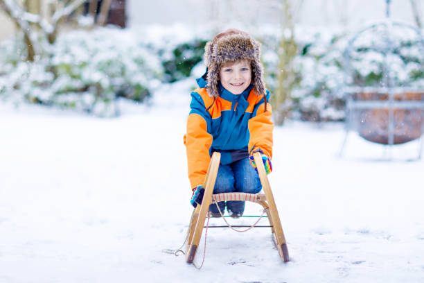 kleine kind junge schlittenfahrt im winter zu genießen - little boys sled clothing slide stock-fotos und bilder