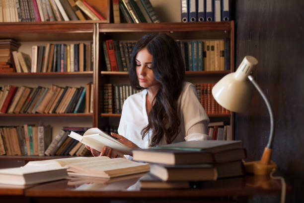 istock girl is preparing for the exam reading book at the library 866517854