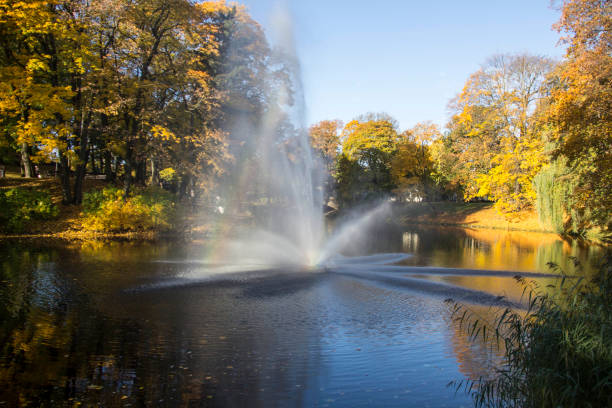 istock Fountain and rainbow in Riga Canal that flows through Bastion park autumn background with colored leaves (Bastejkalns). 866522652