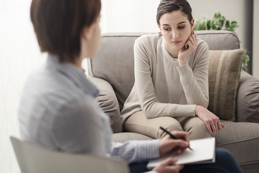 Young female patient talking with her therapist in the office, mental health and psychotherapy concept