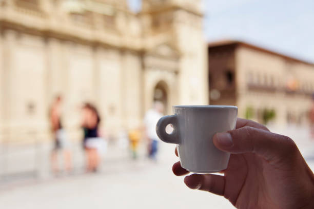 closeup of a young man having a coffee in front of the Cathedral-Basilica of Our Lady of the Pillar in Zaragoza, Spain