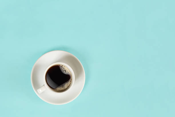 A cup of black coffee on blue background. View from above