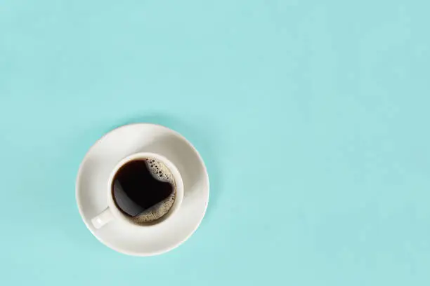 Photo of A cup of black coffee on blue background. View from above
