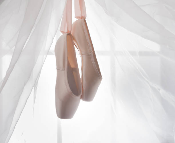 istock Pink ballet pointe shoes hanging on window 866523650