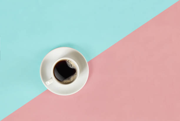 A cup of black coffee on blue and pink background. View from above