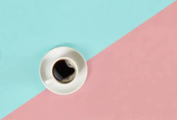 Photo of A cup of black coffee on blue and pink background. View from above