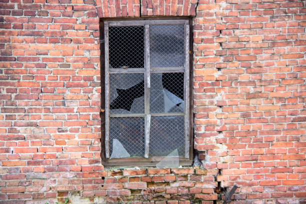 A closeup view of a damaged window framed within a rustic environment, evoking feelings of decay and strong nostalgia
