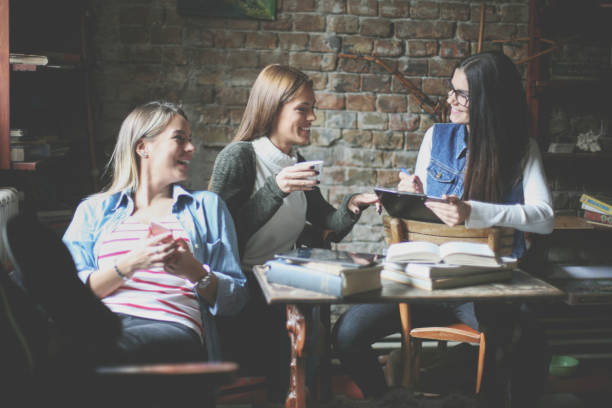 istock Three students girls in cafe having funny conversation. 866534124