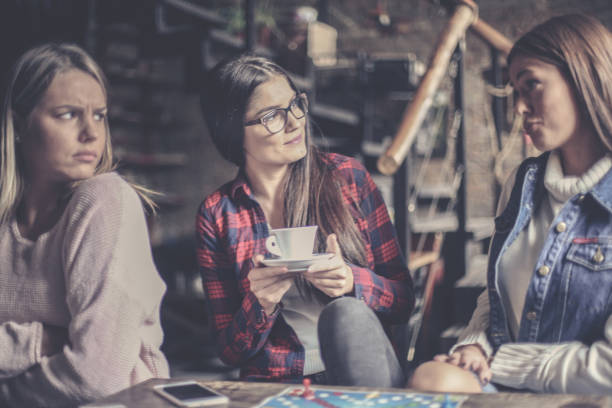 istock Three happy girls playing board game and having serious conversation 866535094