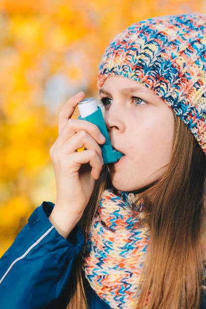 jeune fille à l’aide d’inhalateur asthme dans un parc - inhalation anthrax photos et images de collection