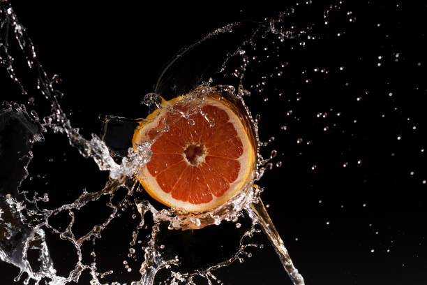 свежий грейпфрут с брызгами воды - orange black horizontal saturated color стоковые фото и изображения