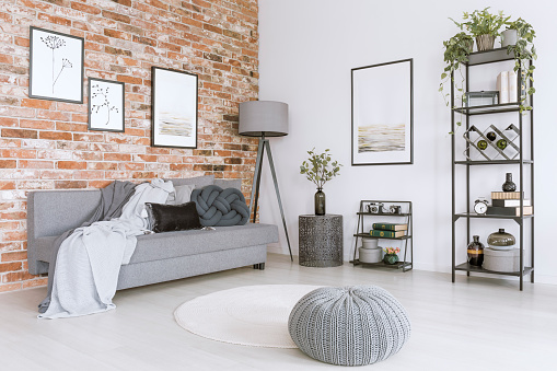 White and gray living room with knit pouf, round rug and modern, metal lamp
