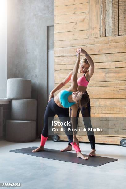 Young Woman With Yoga Instructor In Fitness Class Triangle Pose Stock Photo - Download Image Now