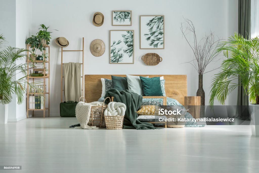 Wall with hats and posters White wall with straw hats and handmade posters in room with king-size bed with pillows Home Decor Stock Photo