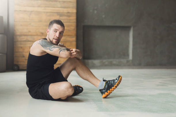 istock Handsome young man lace shoes at gym after training 866548138