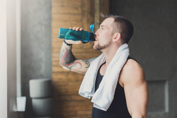 istock Handsome thirsty young man in gym, drinking water from bottle 866548778