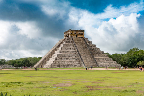 Chichen Itza Pyramids Mexico People visiting the UNESCO world Heritage Site of Chichen Itza during a cloudy summer day. 1.4 million tourists visit the pyramid ruins outside of the city of Cancun every year. kukulkan pyramid photos stock pictures, royalty-free photos & images
