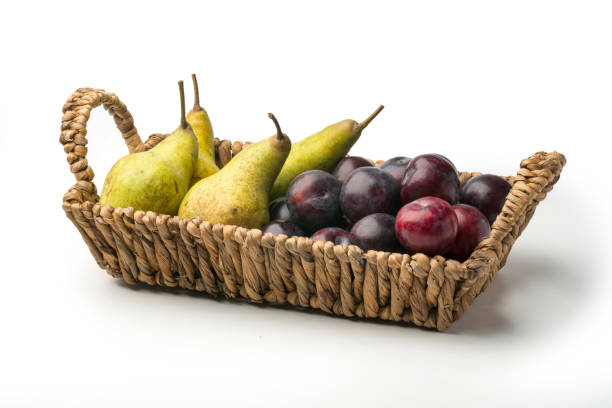 Pears and plums in basket on white background