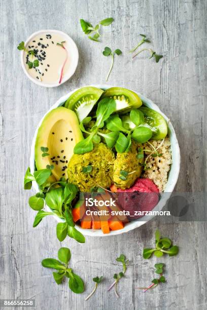 Middle Eastern Style Buddha Bowl With Green Falafel Quinoa Butternut Squash Tomatoes Avocado Beetroot Hummus Micro Greens And Tahini Sauce Stock Photo - Download Image Now