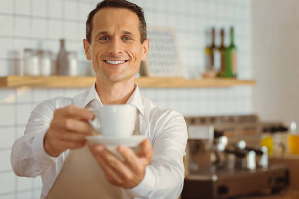 istock Happy joyful man offering you a cup of coffee 866556612